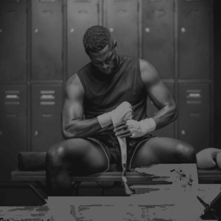 Een atletische mannelijke bokser zit in de kleedkamer en wikkelt een bandage om zijn hand.