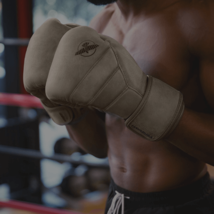 Een close-up van een bokshandschoen, gedragen door een atleet met een zichtbare gespierde torso en tatoeages.