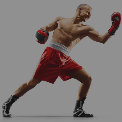 Een gespierde bokser in rode shorts en bokshandschoenen staat in een aanvalshouding met een sterke vuist naar voren.