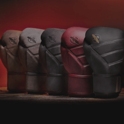 Een rij van bokshandschoenen in verschillende kleuren, met het logo van het merk zichtbaar op de polsband, geplaatst tegen een rode achtergrond.