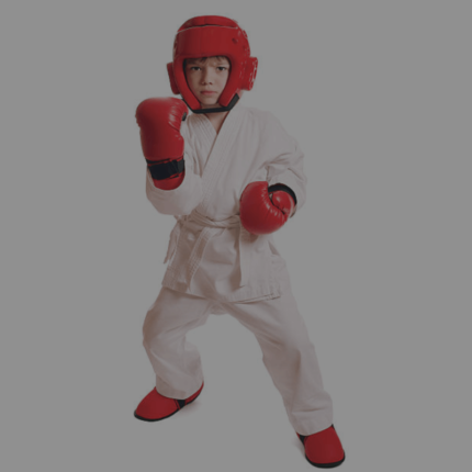 Een kind in een karate uniform met rode bokshandschoenen en een hoofdbeschermer, klaar voor training.