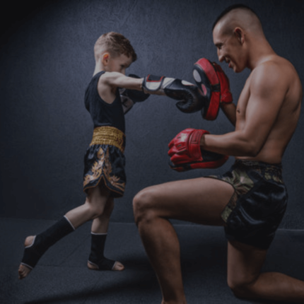 Een oefening tussen een volwassen mannelijke vechtsporter en een jongen, beide in gevechtshouding.