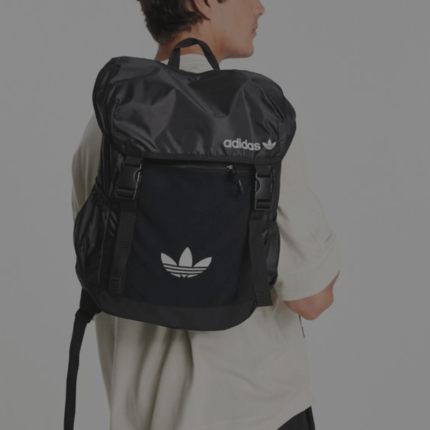 Een persoon draagt een zwarte rugzak met een bekend sportmerk logo, gezien van achteren.