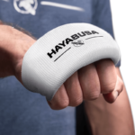 Hand van een persoon die een witte Hayabusa handwrap draagt met het logo zichtbaar bovenop de knokkels.