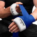 Een persoon wikkelt een blauwe bandage over een witte Hayabusa handwrap om de pols.