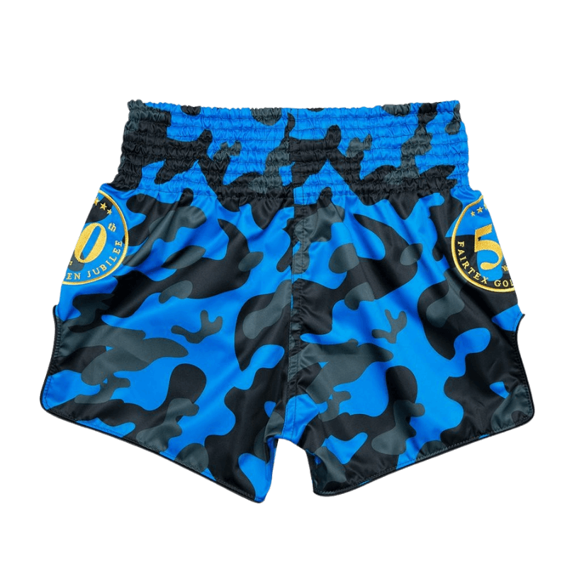 Muay Thai shorts met blauwe camouflageprint, een gele band rond de taille met het 15-jarige jubileumlogo van Fairtex en gouden accenten op de zijkanten.