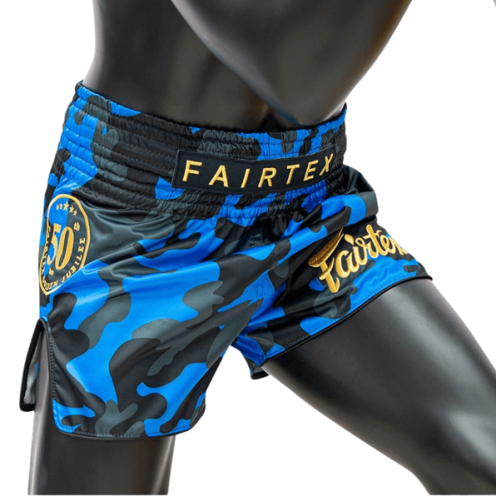 De Muay Thai shorts gedragen door een mannequin, tonen de blauwe camouflageprint, het 15-jarige jubileumlogo van Fairtex op de tailleband en het gouden Fairtex logo op de zijde.