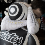 Een vechter in houding draagt Fairtex-trainingsequipment, met de focus op de beschermende gear.